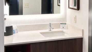 A hotel bathroom with a white sink, a mirror, and a towel rack.