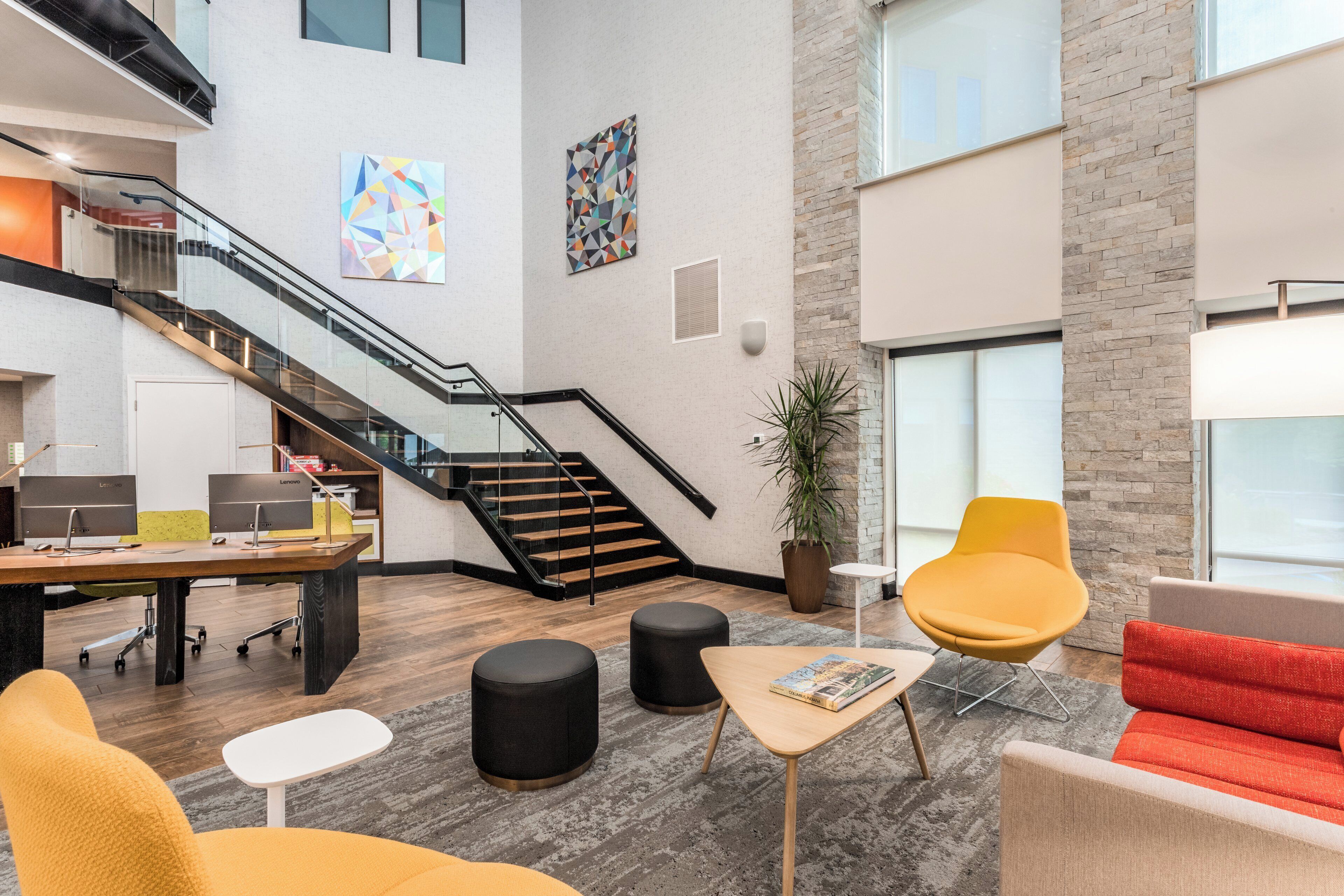 Un intérieur moderne comprenant un escalier, un coin salon et un bureau équipé d’ordinateurs.