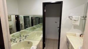 A modern bathroom with a large bathtub, a separate shower area, and a vanity with a mirror. - Portside Inn & Suites (San Pedro)