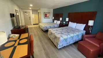 Een hotelkamer met twee bedden, een bureau, een stoel en een bank.