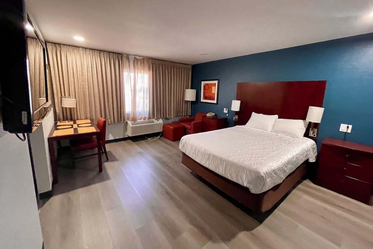 Ein Hotelzimmer mit einem großen Bett, einem Schreibtisch, einem Stuhl und einem Fernseher.