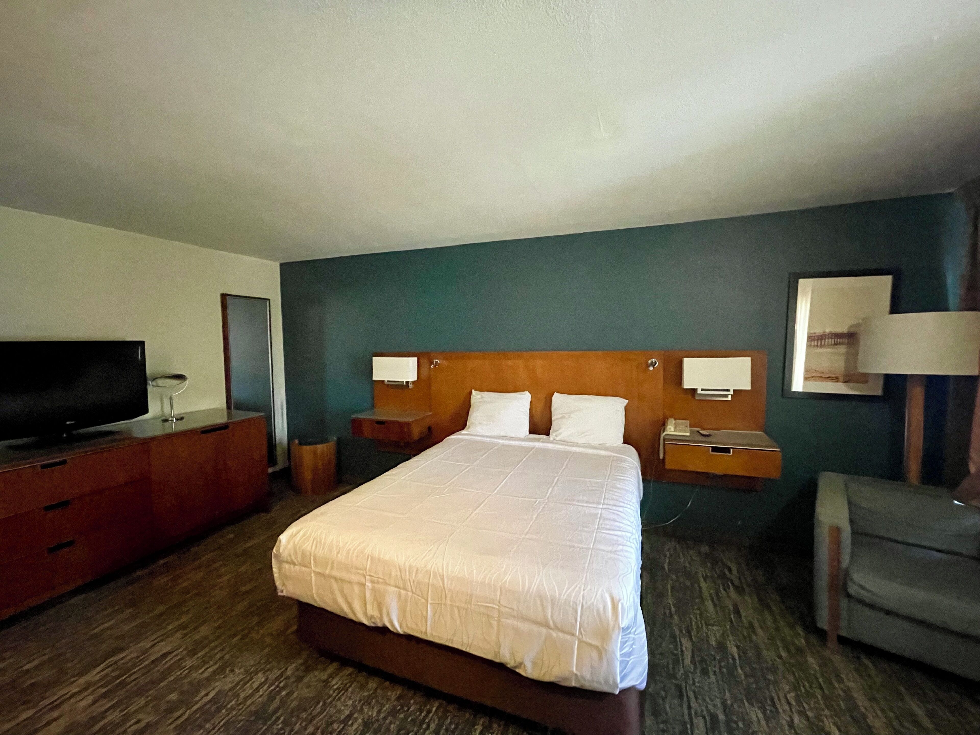 Una habitación de hotel con una cama grande, televisión, escritorio y una silla.
