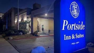 Une enseigne indiquant l’emplacement de l’hôtel Portside Inn & Suites, offrant une vue dégagée sur l’entrée du bâtiment et sur les aménagements paysagers.
