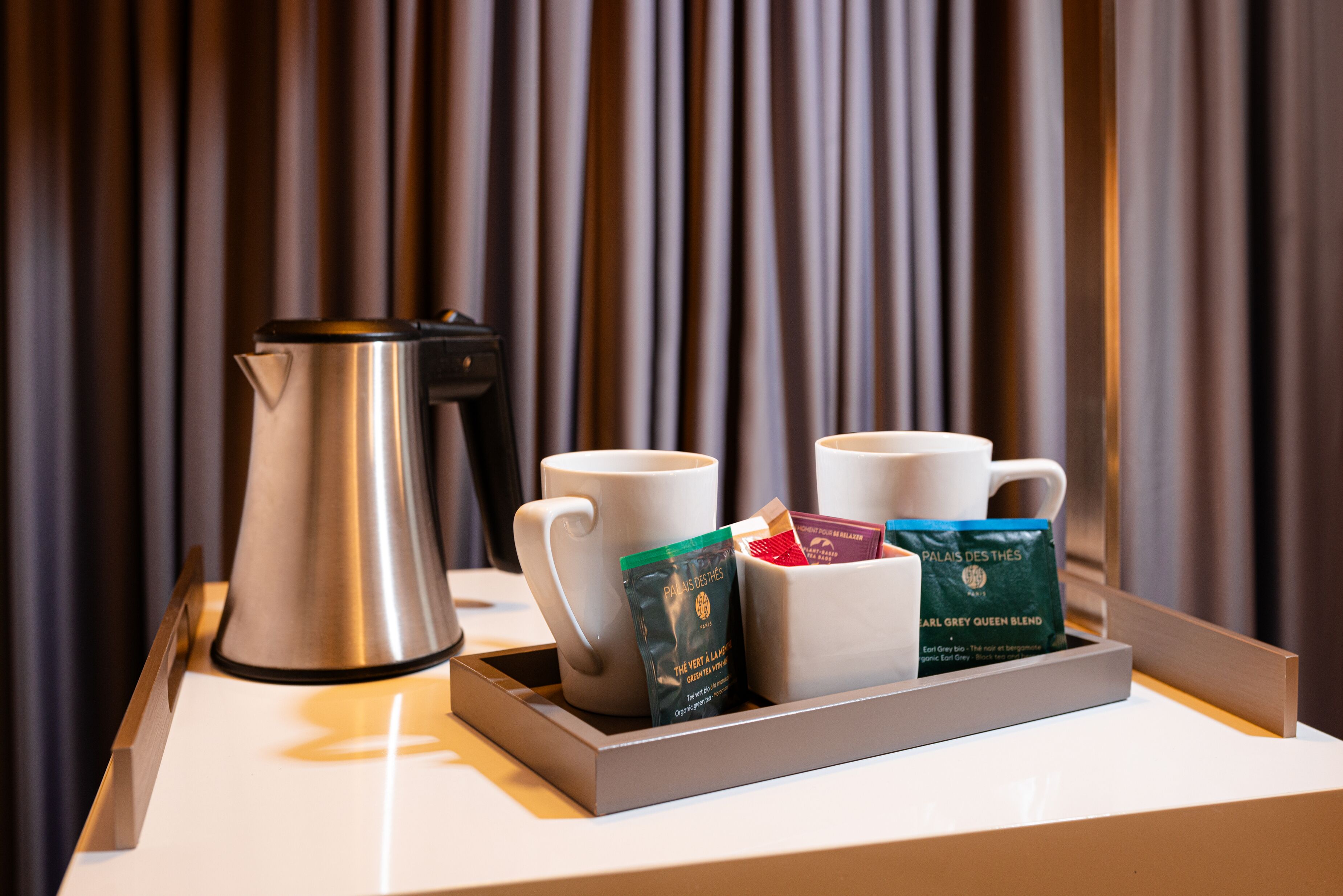 Un safataire amb una cafetera, dues tasses i dos sobres de cafè damunt d'una taula.