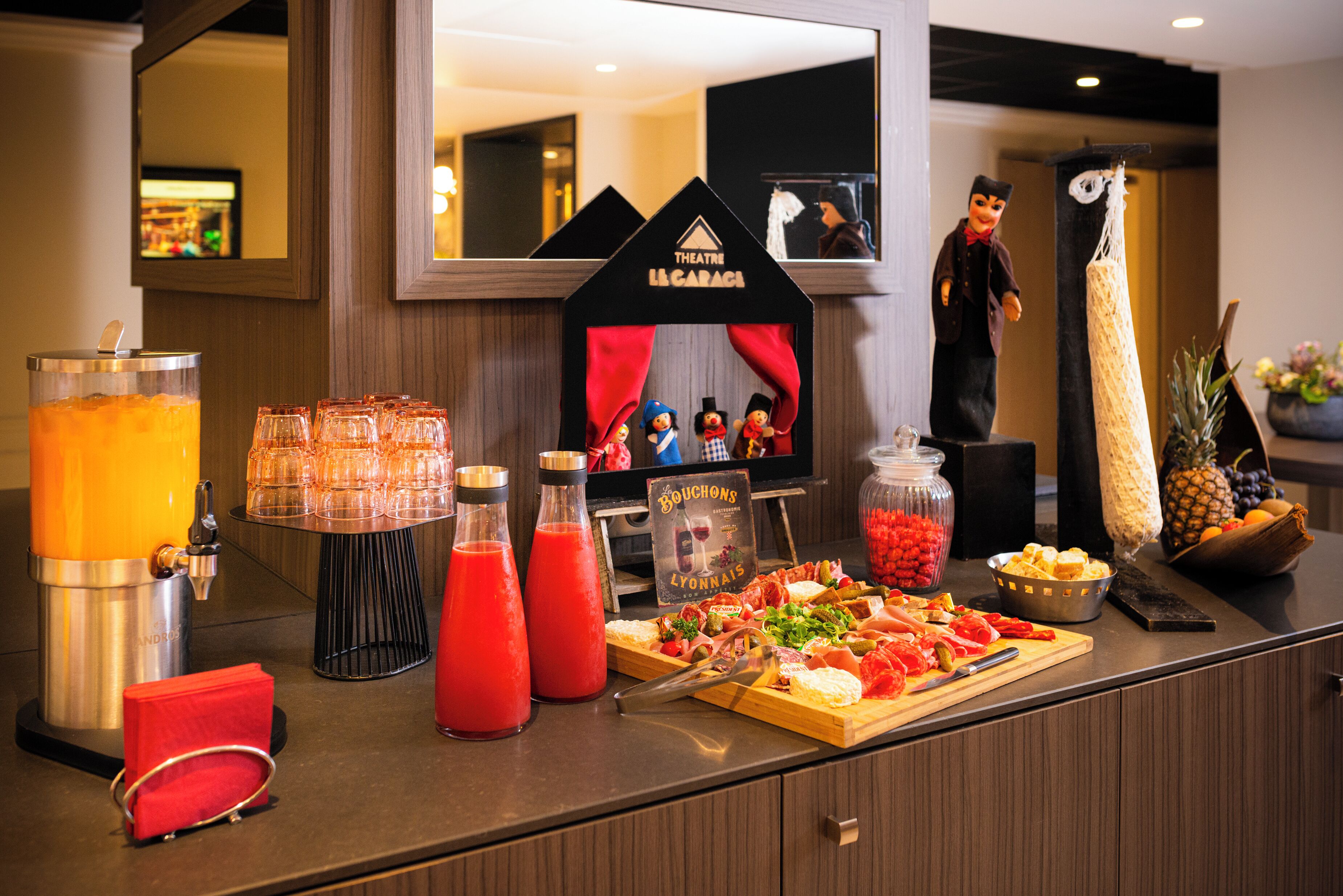 Mostrador buffet con diversos alimentos, bebidas y un cartel que indica 'Bouchons Lyonnais'.