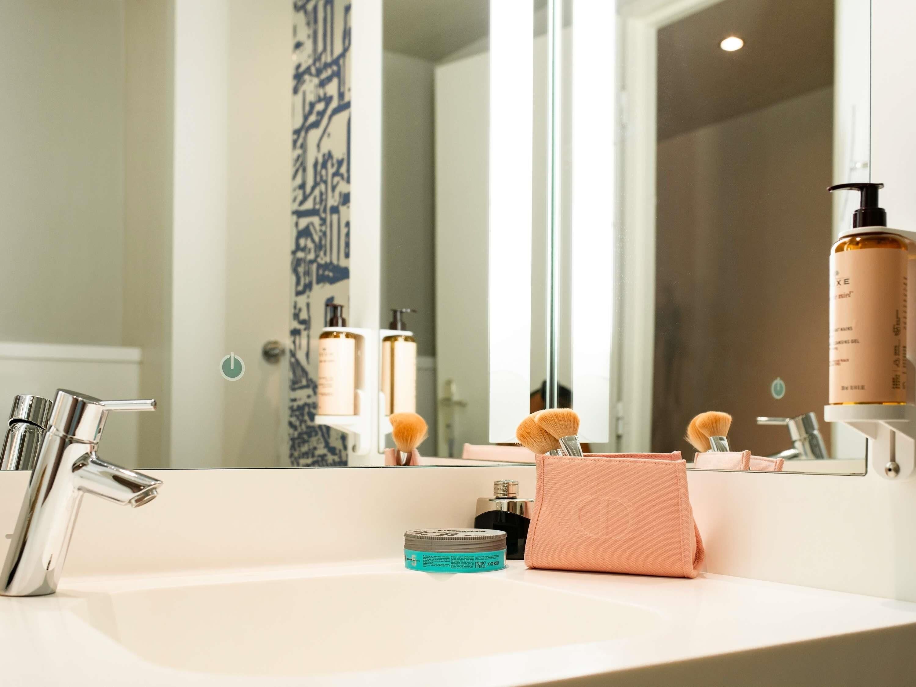 Un baño con lavabo, espejo y artículos de aseo.