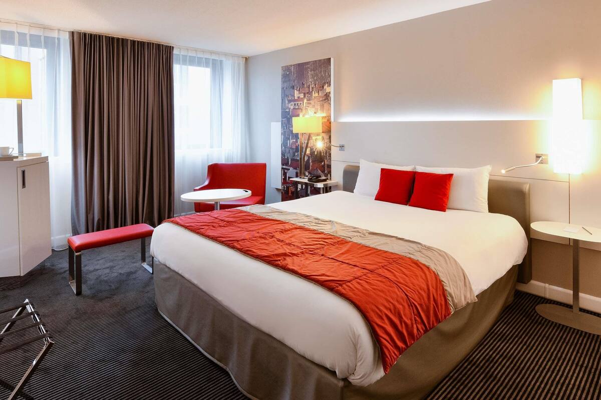 Una camera d'albergo con un letto, una scrivania, una sedia e una panca.