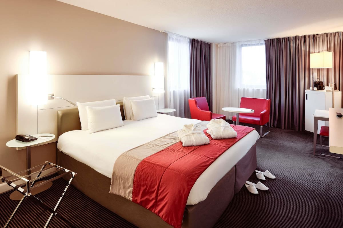 Una camera d'albergo con un letto, una scrivania, una sedia, una lampada e un telefono.