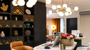 Un interior moderno con decoración en negro y dorado, una mesa redonda de mármol, una computadora portátil y una silla.