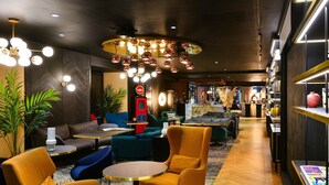 Un moderno vestíbulo de hotel con zona de estar, bar y estantería.