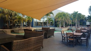 An outdoor seating area with wicker furniture and a pool.