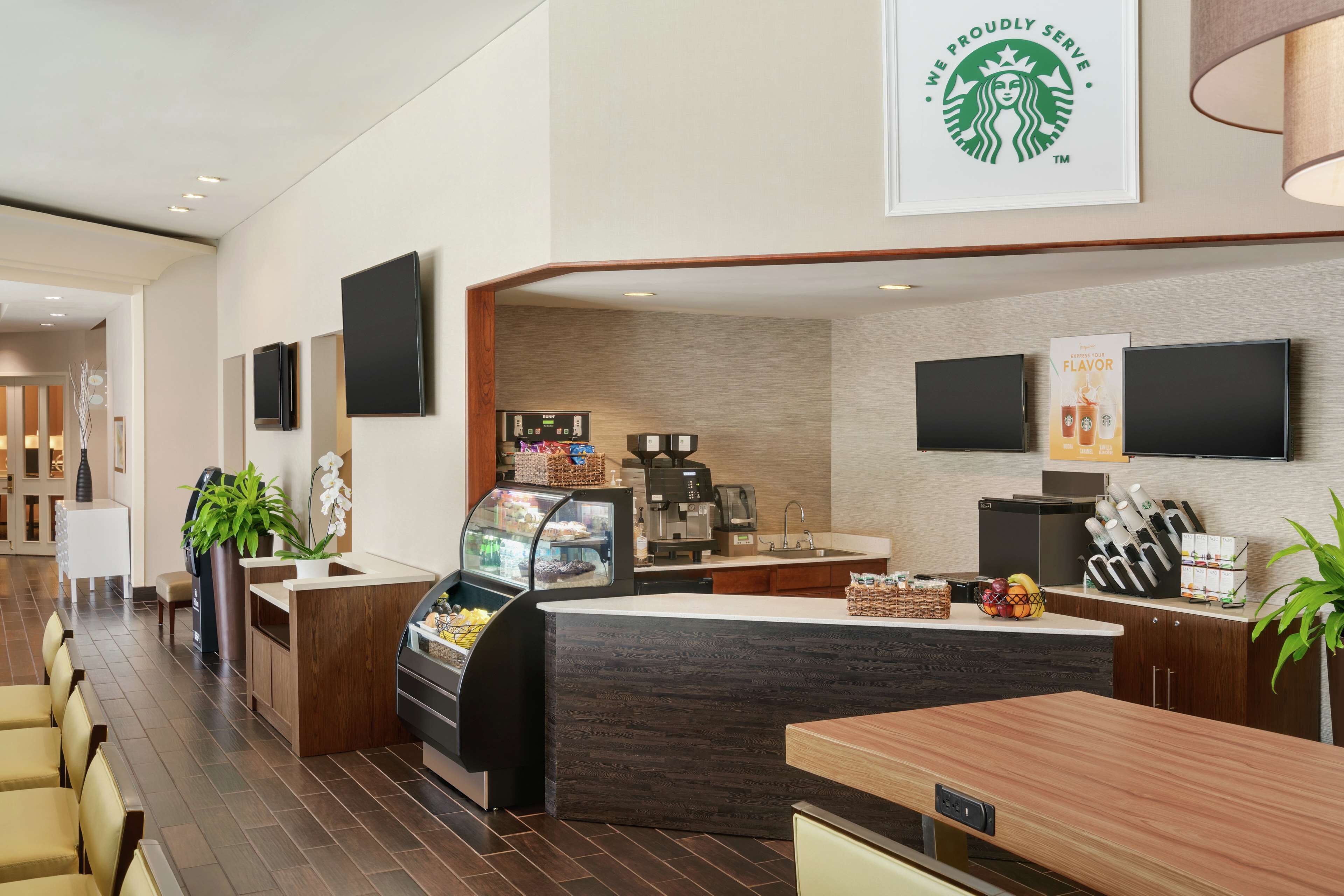 Eine moderne Hotelhalle mit einem Starbucks-Stand, Sitzgelegenheiten und einer Kaffeemaschine.