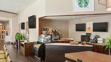Eine moderne Hotelhalle mit einem Starbucks-Stand, Sitzgelegenheiten und einer Kaffeemaschine.