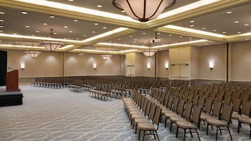 A conference room with rows of chairs, a podium, and multiple ceiling lights.
