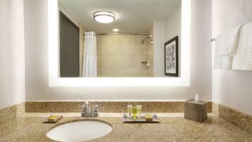 A bathroom with a large mirror, a sink, and a shower.