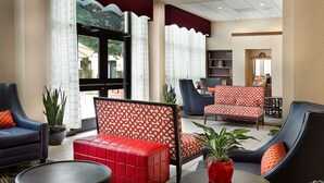 Eine Lobby mit Sitzbereichen, einem Couchtisch und einem Bücherregal.