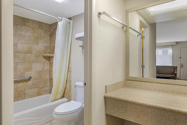 A bathroom with a bathtub, toilet, and a mirror.