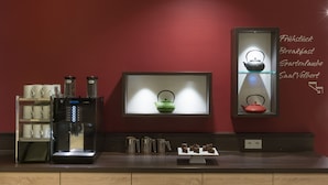 A coffee machine, tea kettles, and a display of tea sets on a counter.