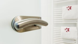 A metallic door handle on a white door.