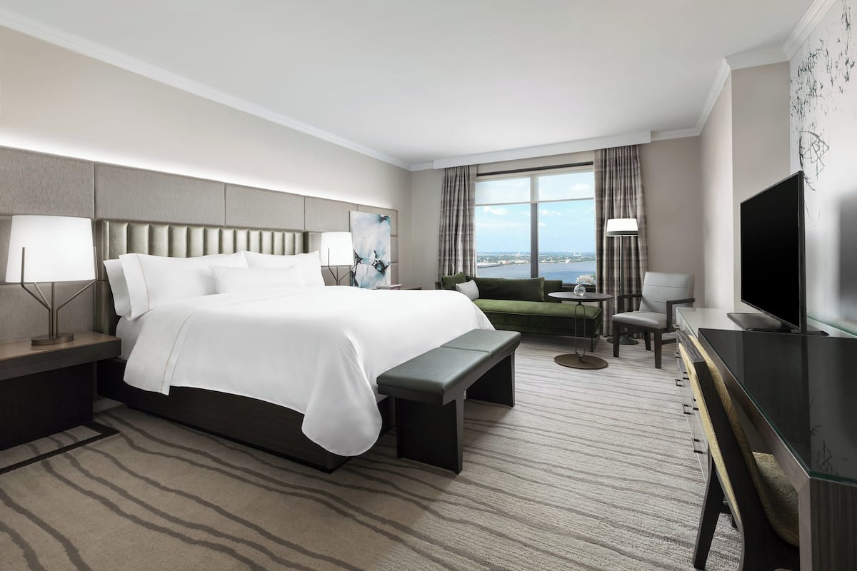 A modern hotel room with a large bed, a desk, a chair, and a television.
