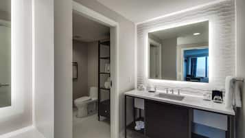 A modern bathroom with a white vanity, dark cabinet, and a large mirror.