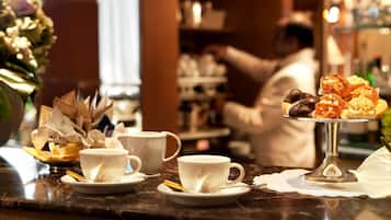 Un caffè con un bancone in marmo, tazze bianche e un vassoio di pasticcini.