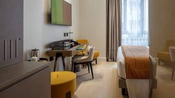 Una camera d'albergo con un letto, una scrivania con una sedia, una televisione e una finestra con tende.