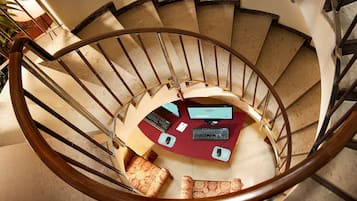 Un escalier en colimaçon avec un bureau et deux chaises en bas.