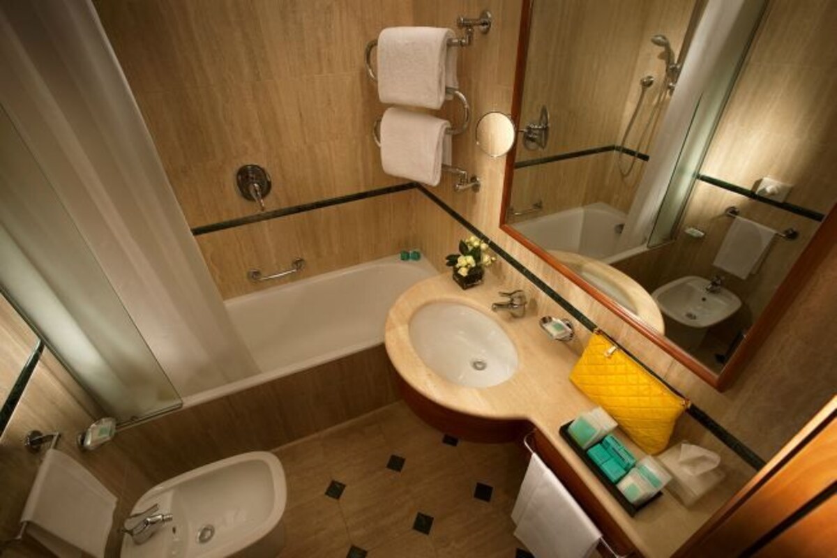 A bathroom with a bathtub, a sink, a toilet, and a mirror.