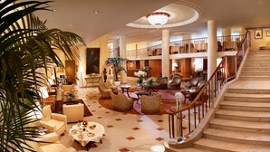 A spacious lobby with a grand staircase, multiple seating areas, and a large chandelier. - Hotel Cavour (Milan)