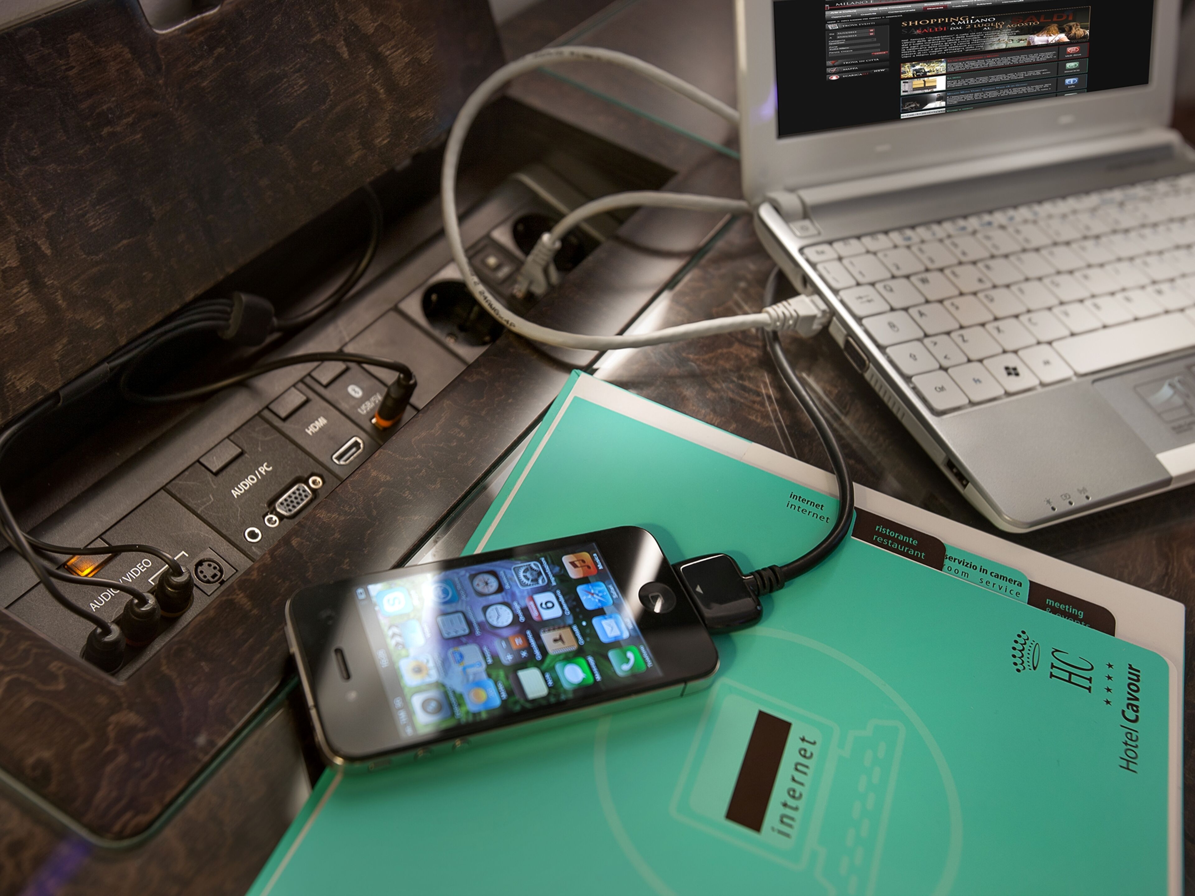 A laptop, a smartphone, and a hotel card on a desk.