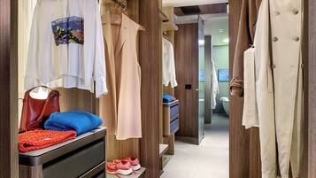 A modern hotel room with a walk-in closet, wooden paneling, and a large mirror.