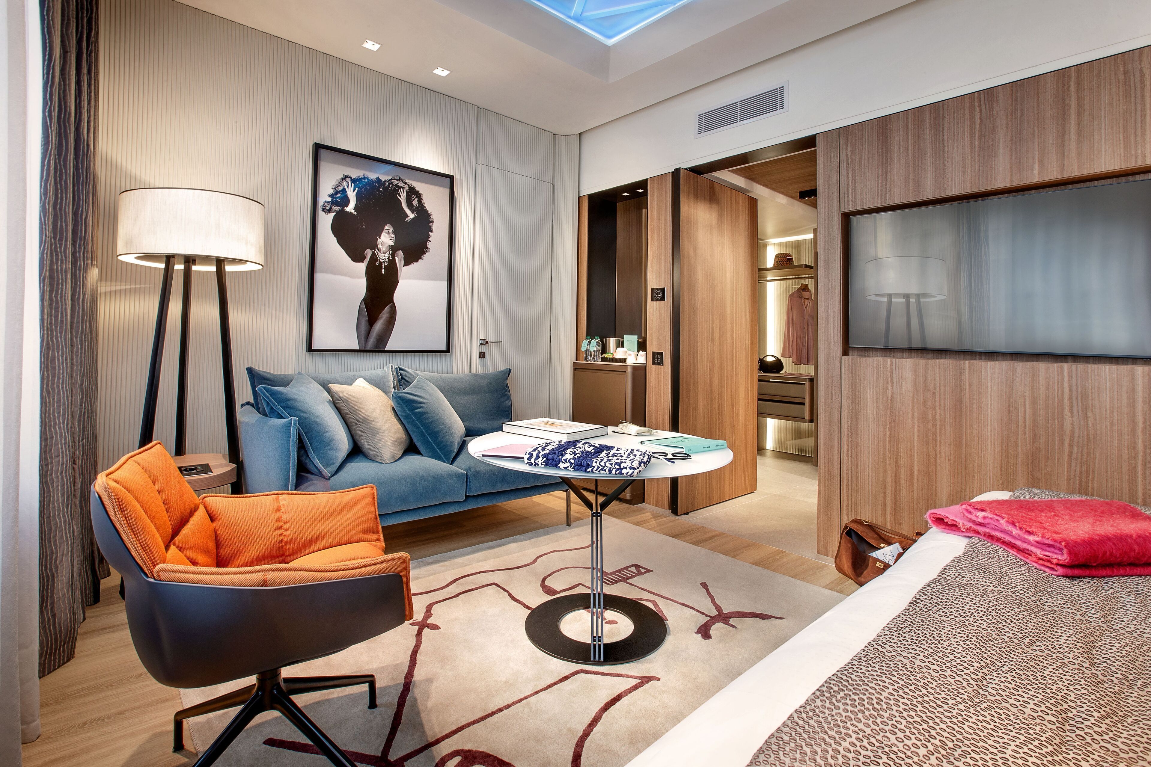 Een moderne hotelkamer met een bank, fauteuil en een kleine tafel met een lamp.