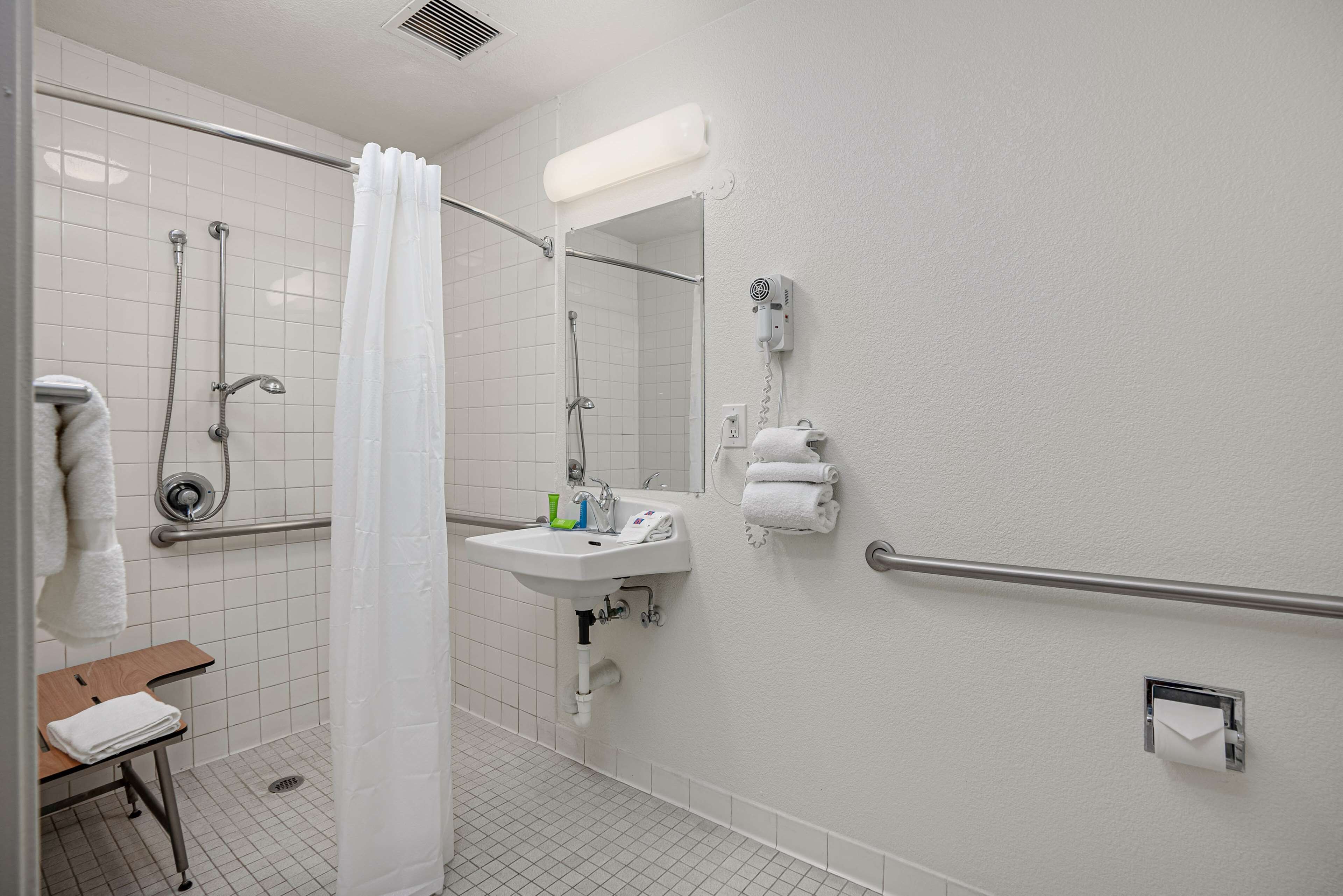 A bathroom with a shower, sink, and hand dryer.