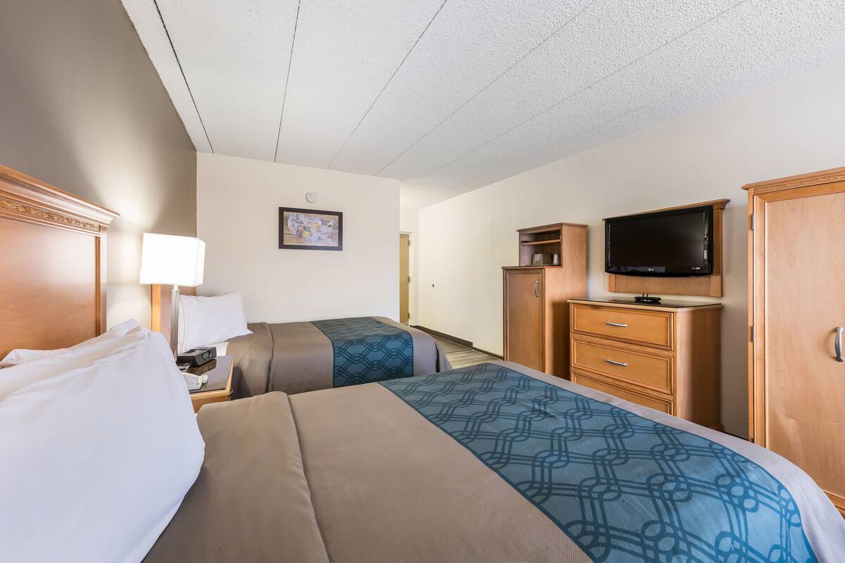 Une chambre d’hôtel avec deux lits, une télévision, un bureau avec une lampe et une armoire.