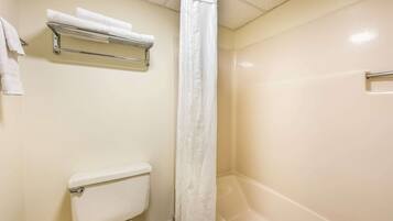 A bathroom with a toilet, a shower with a curtain, and a towel rack with towels.