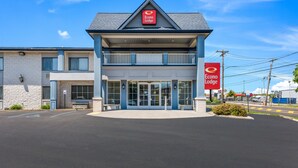 Un edificio de Econo Lodge de dos pisos, con una entrada destacada, estacionamiento y un cielo azul despejado.