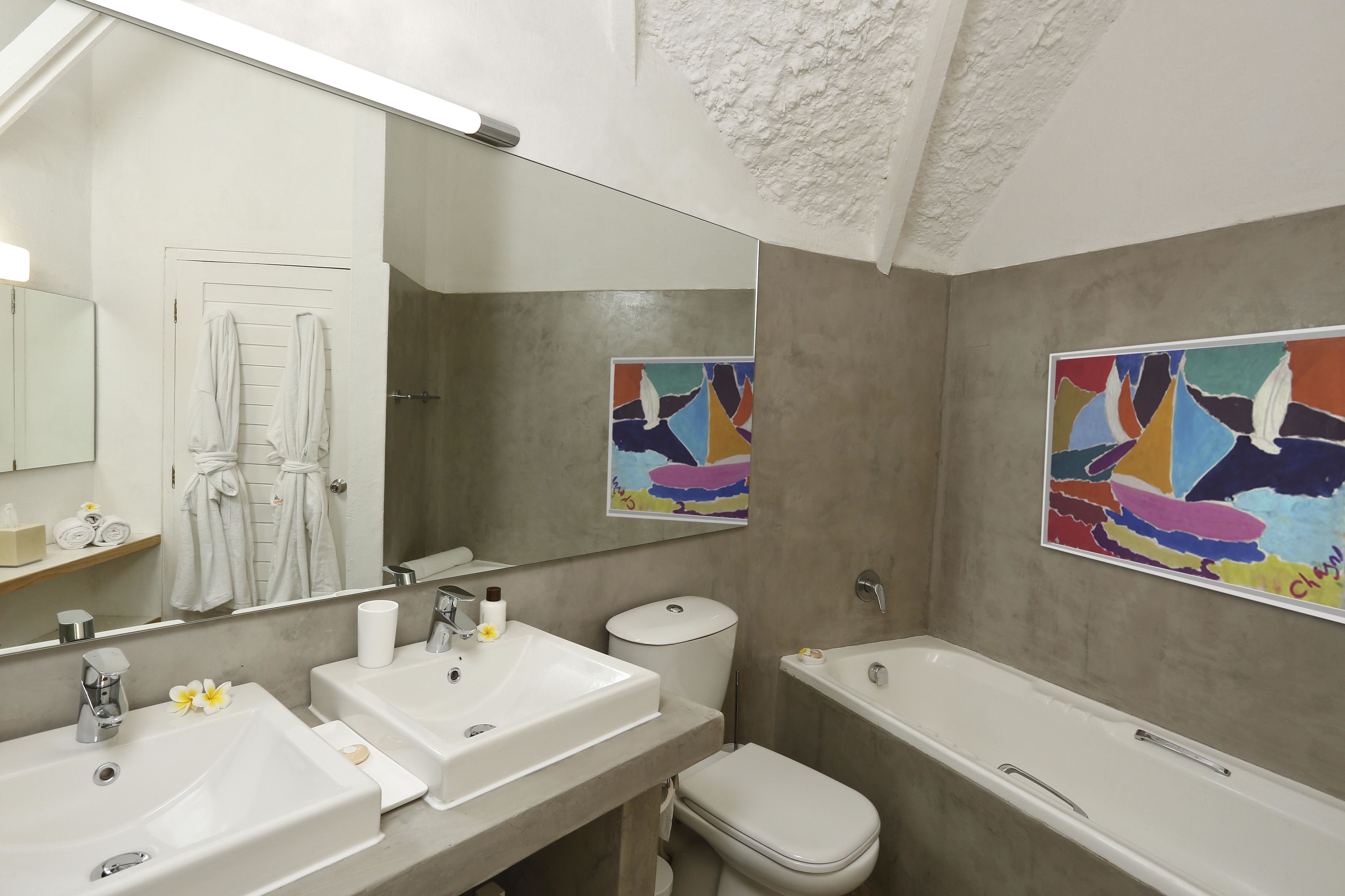 Une salle de bain moderne avec deux lavabos, des toilettes et une baignoire. On trouve des serviettes et des articles de toilette sur le comptoir.