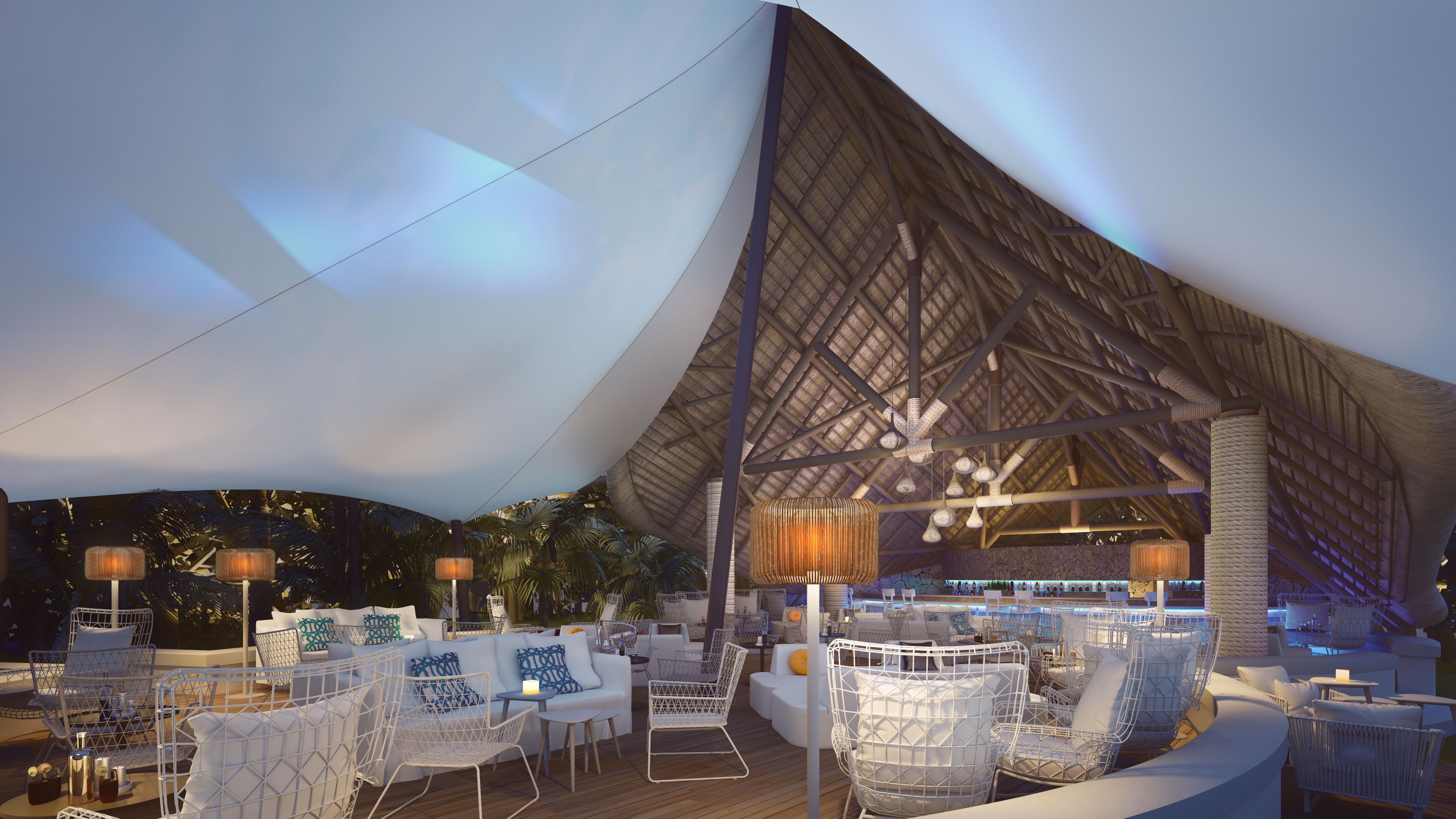 Un espace extérieur aménagé avec des chaises en fil de fer blanc, une terrasse en bois et une grande structure dotée d’un toit de chaume.