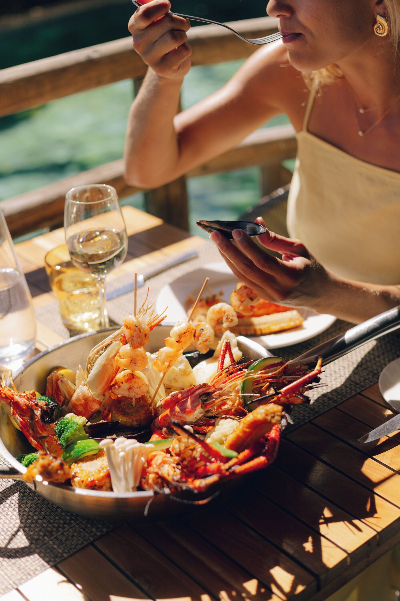A dining table with seafood, wine glasses, and a smartphone.