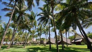 A tropical resort with palm trees and thatched-roof buildings. - La Pirogue Mauritius (Flic-en-Flac)