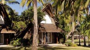 A tropical resort with palm trees, thatched-roof buildings, and a well-maintained lawn. - La Pirogue Mauritius (Flic-en-Flac)