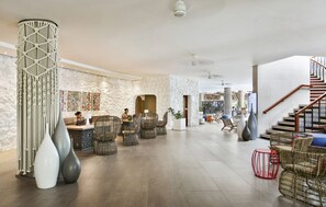 A spacious lobby with a reception desk, seating area, and a staircase.