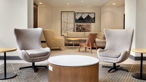 A modern lobby with two grey armchairs, a round coffee table, a sofa, and a small table with a chair. - Holiday Inn Houston Intercontinental Airport by IHG (Houston)
