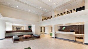 A spacious lobby with a reception desk, seating area, and a staircase to an upper level. - Holiday Inn Houston Intercontinental Airport by IHG (Houston)