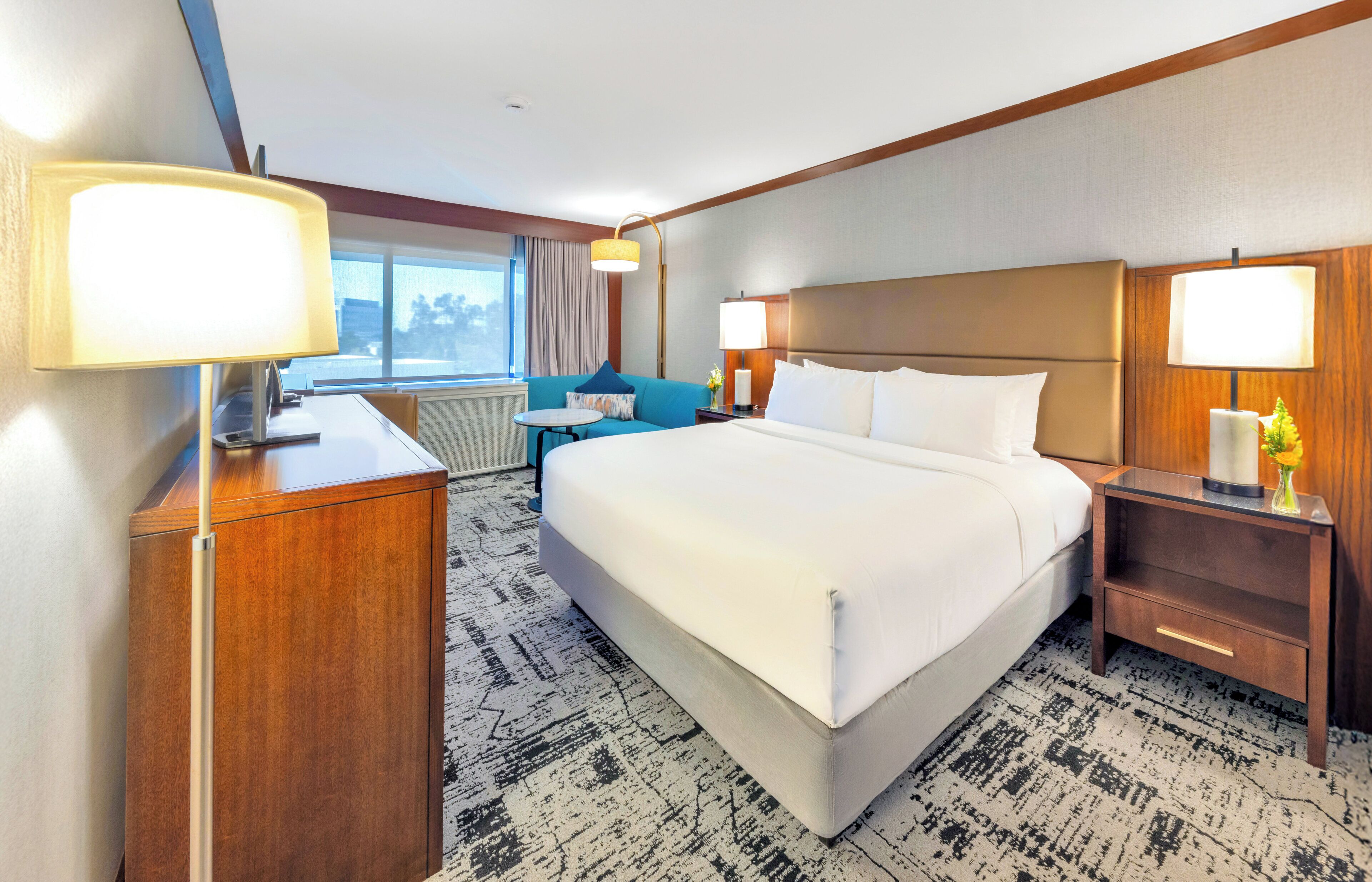 A hotel room with a large bed, bedside tables, a desk, and a chair.