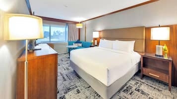 A hotel room with a large bed, bedside tables, a desk, and a chair.
