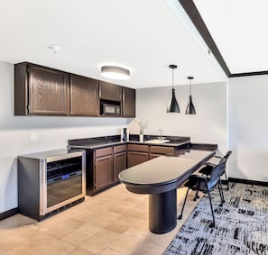 A modern kitchen with dark wood cabinets, a built-in microwave, stainless steel appliances, and pendant lighting. - Crowne Plaza Hotel Foster City - San Mateo by IHG (Foster City)