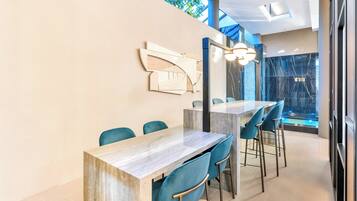 Un comedor moderno con una mesa larga y sillas azules, un adorno en la pared y vista a una cascada a través de un muro de cristal.