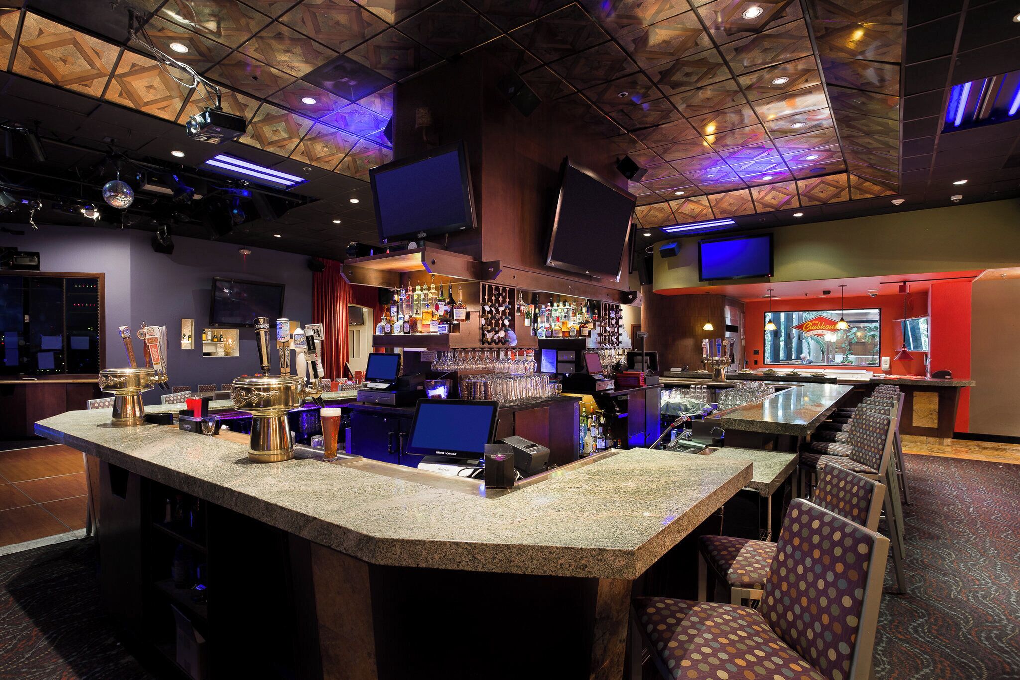 A bar area with a counter, bar stools, and a variety of liquor bottles.